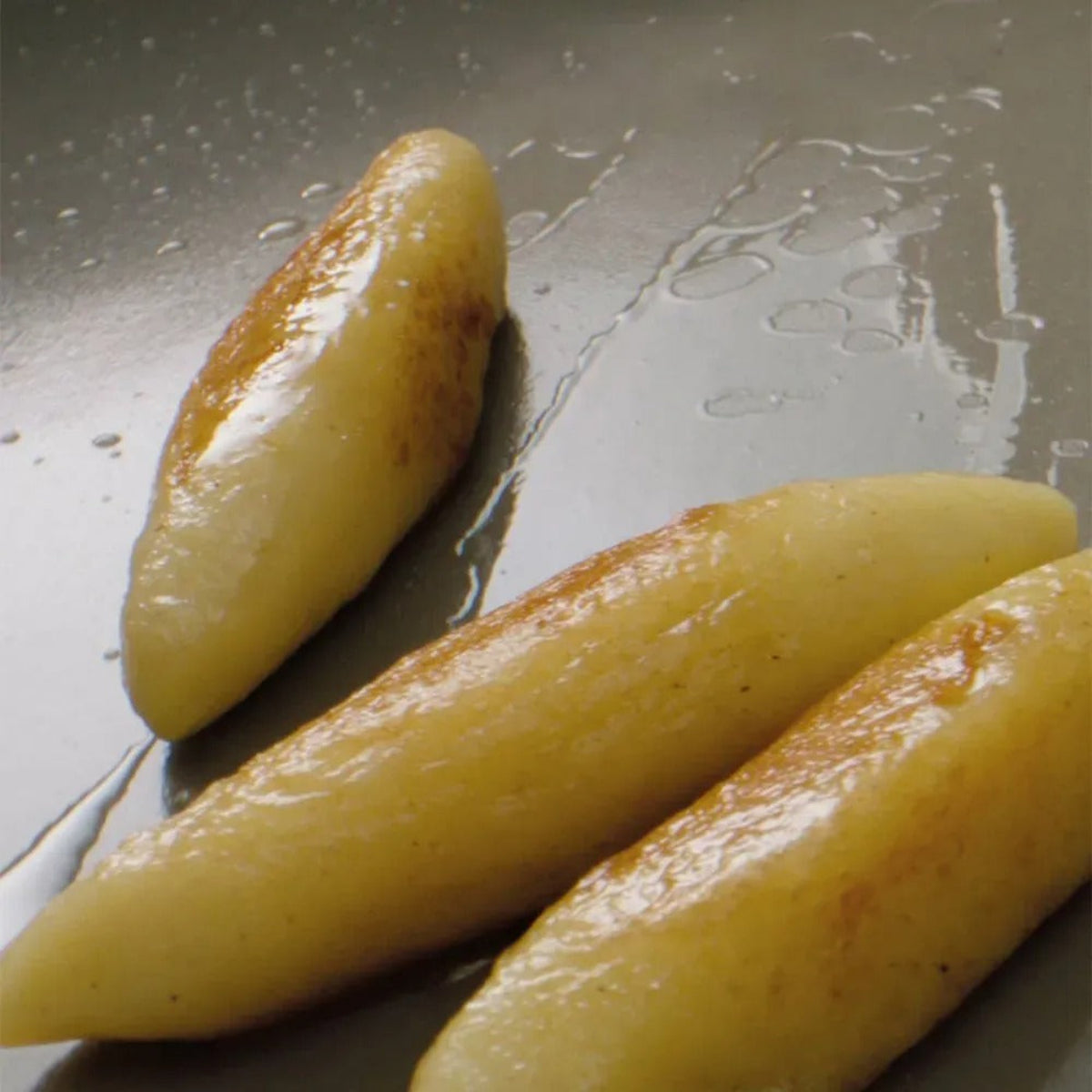 Three peeled potatoes on a metallic surface