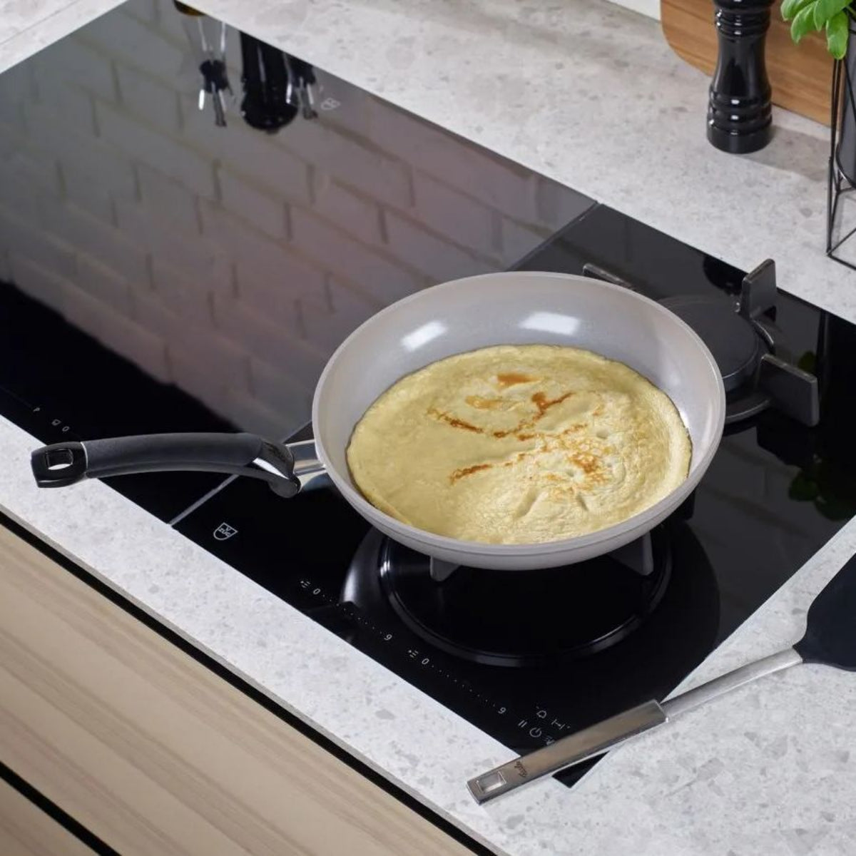Omelette cooking in a pan on an electric stove with a kitchen background.