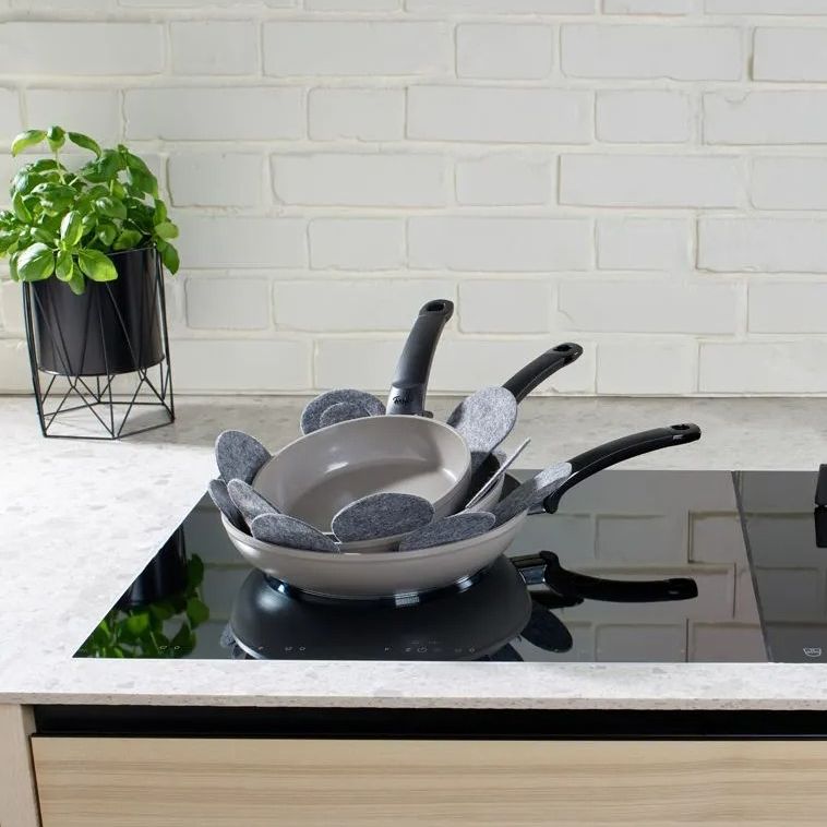 Set of cookware on a stove with a white tiled wall in the background
