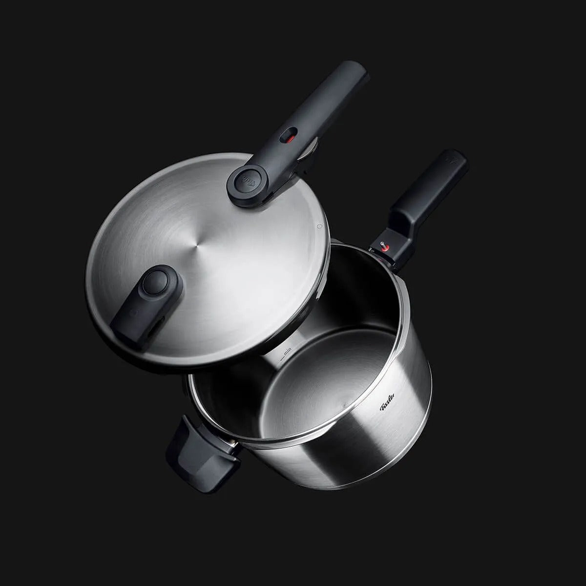 Stainless steel pressure cooker on a black background