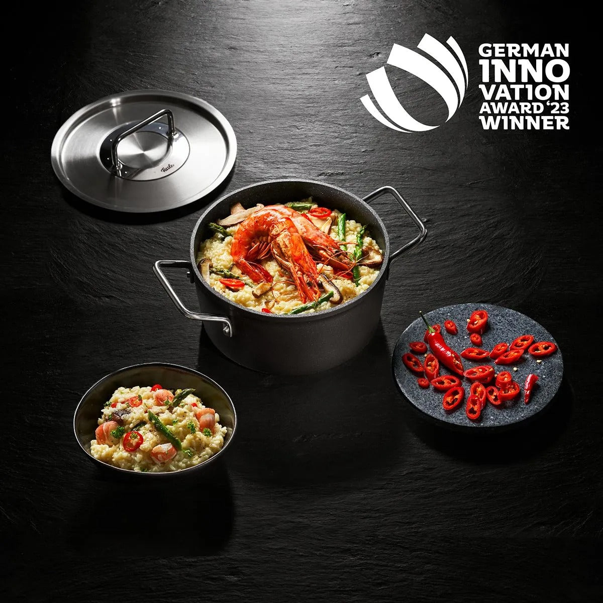 Cooking pot with food on a dark surface, featuring the German Innovation Award 2023 winner logo.
