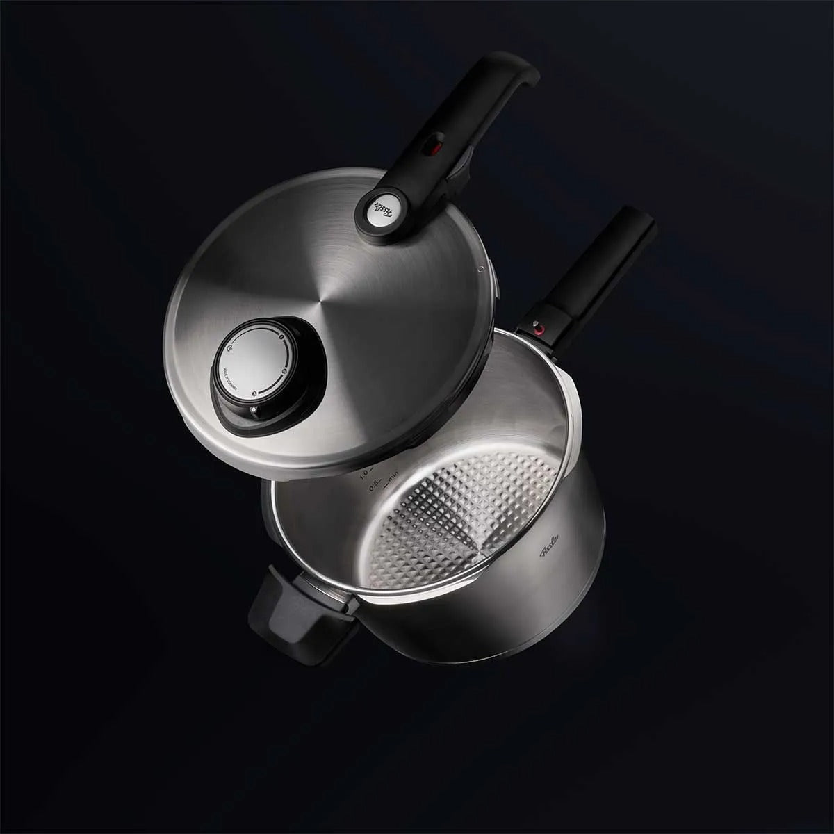 Stainless steel pressure cooker on a black background