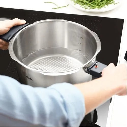 Stainless steel pot with a perforated bottom on a stove