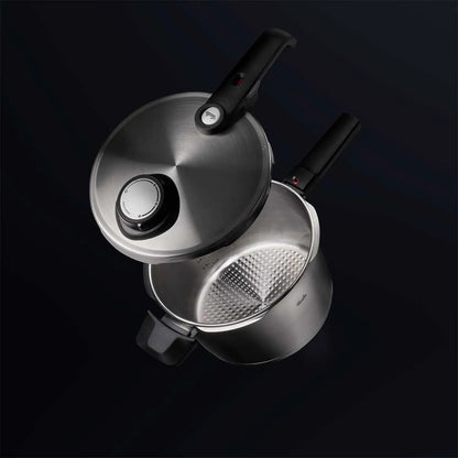Stainless steel pressure cooker on a black background