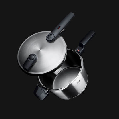 Stainless steel pressure cooker on a black background